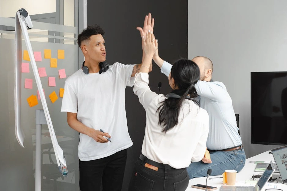 A diverse team of professionals collaborating around a table with blueprints and a model of a green building.